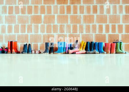 Regenstiefel aus Gummi auf dem Boden am Eingang einer College-Klasse, ohne jemand, mit Platz für Text. Stockfoto