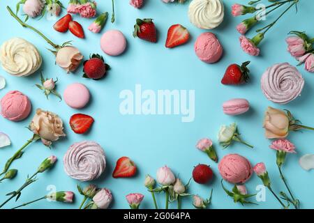 Makronen, Sumpflandschaften, Blumen und Erdbeeren auf blauem Hintergrund Stockfoto