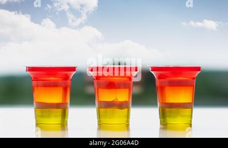 Drei Gläser bunt gestreiftes Gelee auf natürlichem Hintergrund. Regenbogengelee für Kinderparty. Nahaufnahme. Stockfoto