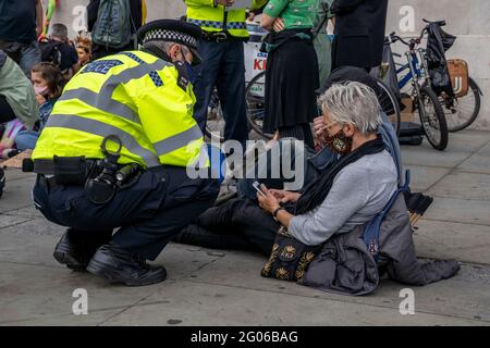 LONDON, Großbritannien – Metropolitan Police Officers interagieren mit den Demonstranten der Extinction Rebellion, während sie während eines Protestes zum Klimawandel auf der Straße sitzen Stockfoto