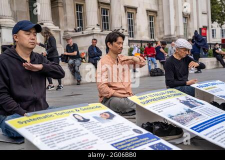 LONDON, Großbritannien - Asiatische Männer meditieren während einer Demonstration gegen die Verfolgung und Folter von Falun Gong-Praktizierenden durch die Kommunistische Partei Chinas Stockfoto