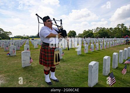 Brian Creel von Palm Beach Pipes & Drums spielt die Pfeifen auf dem South Florida National Cemetery Sonntag, 30. Mai 2021 in Lake Worth, Florida. Freiwillige auf dem Friedhof legten US-Flaggen auf etwa 25,000 Gräber, in denen Angehörige des Militärs begraben werden, um sich auf eine Gedenkfeier am Montag vorzubereiten. (Foto von David Santiago/Miami Herald/TNS/Sipa USA) Stockfoto