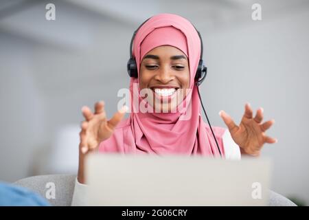 Schwarze Islamische Dame In Hijab Und Headset Mit Videoanruf Auf Dem Laptop Stockfoto