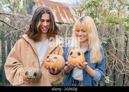 Ein paar lachende Teenager mit halloween-Kürbissen, die Spaß haben Stockfoto