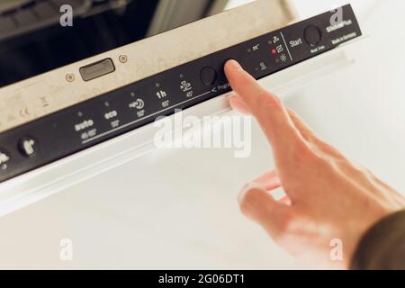 Man wählt das Eco-Modus-Programm auf dem Bedienfeld des Geschirrspülers. Stockfoto