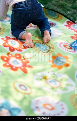 Das kleine Mädchen kriecht auf einer farbigen Decke. Nahaufnahme Stockfoto