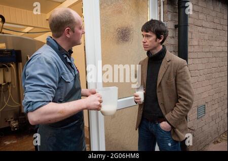 Rory Stewart, der konservative Kandidat des Parlaments für den Penrith und den Wahlkreis der Grenze, sprach mit dem Landwirt Richard Gibson während des Melkens am Morgen. Teil des Wahlkampfs von Rory aus dem Jahr 2010. Castlesteads Farm, Plumpton, Cumbria, Großbritannien. 16 April 2010 Stockfoto