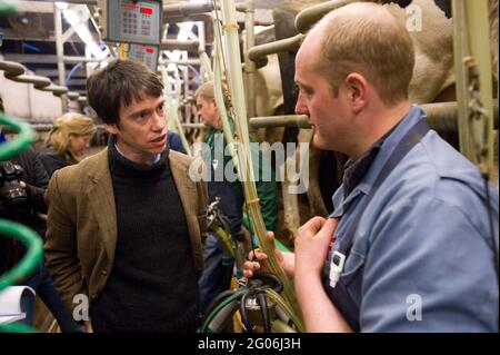 Rory Stewart, der konservative Kandidat des Parlaments für den Penrith und den Wahlkreis der Grenze, sprach mit dem Landwirt Richard Gibson während des Melkens am Morgen. Teil des Wahlkampfs von Rory aus dem Jahr 2010. Castlesteads Farm, Plumpton, Cumbria, Großbritannien. 16 April 2010 Stockfoto