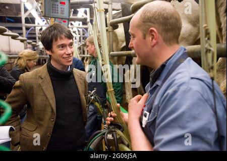 Rory Stewart, der konservative Kandidat des Parlaments für den Penrith und den Wahlkreis der Grenze, sprach mit dem Landwirt Richard Gibson während des Melkens am Morgen. Teil des Wahlkampfs von Rory aus dem Jahr 2010. Castlesteads Farm, Plumpton, Cumbria, Großbritannien. 16 April 2010 Stockfoto