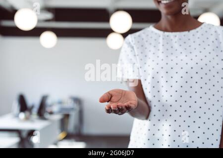 Mittelteil einer lächelnden afroamerikanischen Geschäftsfrau mit offener Hand Stockfoto