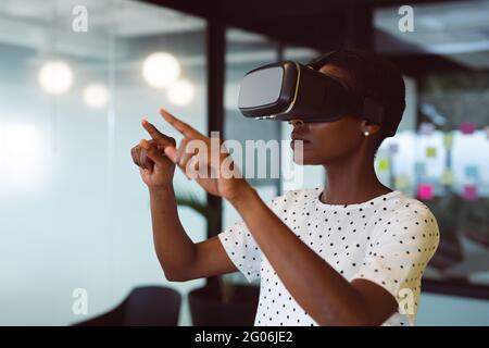 Lächelnde afroamerikanische Frau mit vr-Headset bei der Arbeit Stockfoto