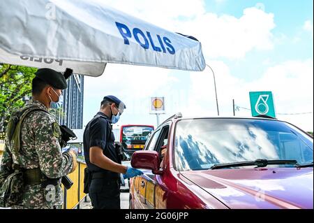 Kuala Lumpur, Malaysia. Juni 2021. Ein Polizist und ein Soldat überprüfen Fahrzeuge an einer Straßensperre in Kuala Lumpur, Malaysia, 1. Juni 2021. Malaysia begann am Dienstag landesweit eine zweiwöchige Sperre, um die COVID-19-Infektionen zu reduzieren. Es dürfen nur wichtige Sektoren arbeiten und es gibt Reisebeschränkungen, um die Menschen in einem Umkreis von 10 km von ihrem Zuhause zu halten. Quelle: Zhu Wei/Xinhua/Alamy Live News Stockfoto