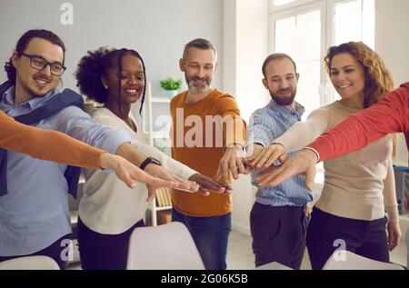 Eine große Gruppe glücklicher, vielfältiger Menschen, die ihre Hände ausstreuen und Handflächen zusammenfügen Stockfoto