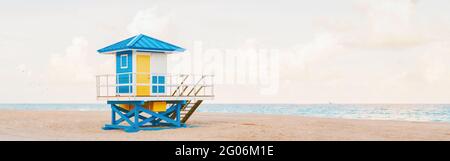 Helle, luftige tropische Florida-Landschaft mit blaugelbem Rettungsschwimmerhaus. American Florida Natur Meerblick mit Rettungsschwimmer Turm, Wasser, Sand und Himmel. Stockfoto