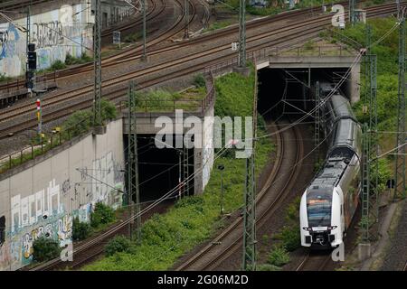 KÖLN, DEUTSCHLAND - 23. Mai 2021: Bahngleise überqueren auf verschiedenen Ebenen, Eingang von zwei Tunneln sowie einem Zug Stockfoto