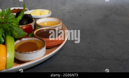 Gourmet Käse Frühstücksteller Idee, Frühstück Vorspeise Teller mit grauem Marmor Hintergrund, Honig, Hagebutten Marmelade, Quitte Marmelade, Butter, Schwarze Oliven, peppe Stockfoto