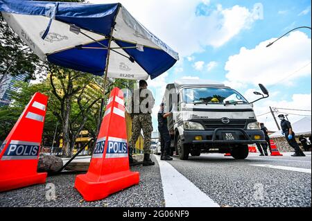 Kuala Lumpur, Malaysia. Juni 2021. Polizisten und ein Soldat überprüfen Fahrzeuge an einer Straßensperre in Kuala Lumpur, Malaysia, 1. Juni 2021. Malaysia begann am Dienstag landesweit eine zweiwöchige Sperre, um die COVID-19-Infektionen zu reduzieren. Es dürfen nur wichtige Sektoren arbeiten und es gibt Reisebeschränkungen, um die Menschen in einem Umkreis von 10 km von ihrem Zuhause zu halten. Quelle: Zhu Wei/Xinhua/Alamy Live News Stockfoto