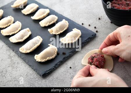 Nahaufnahme der Hände, die auf dem Steintisch in der Küche mit Fleisch Dämpfe machen. Stockfoto