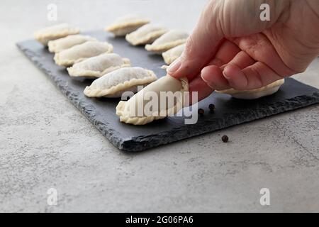 Nahaufnahme der Hand, die mit Fleisch auf dem Steintisch in der Küche staufelt. Stockfoto