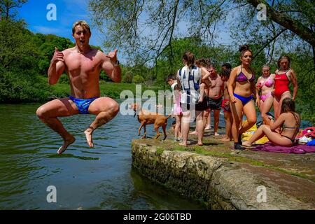 Schwimmer und Sonnenanbeter springen ins Wasser, während sie das heiße Wetter in Warleigh Weir, Bath, am ersten Tag des meteorologischen Sommers genießen. Bilddatum: Dienstag, 1. Juni 2021. Stockfoto