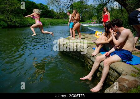 Am ersten Tag des meteorologischen Sommers springt eine Frau ins Wasser, während die Menschen das heiße Wetter in Warleigh Weir, Bath, genießen. Bilddatum: Dienstag, 1. Juni 2021. Stockfoto