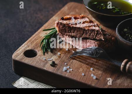 Gegrilltes Rindersteak mit Rosmarin, Gewürzen und Salz auf Schneidebrett. Selektiver Fokus, Nahaufnahme Stockfoto