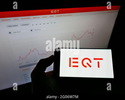 Person, die ein Mobiltelefon mit dem Logo der schwedischen Private-Equity-Firma EQT Partners ab auf dem Bildschirm vor der Unternehmenswebsite hält. Konzentrieren Sie sich auf die Telefonanzeige. Stockfoto