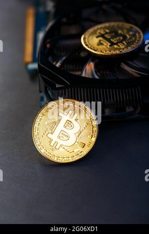 Bitcoin-Münze auf einer leistungsstarken Grafikkarte zum Mining und Sammeln von Kryptowährungskonzepten auf dunklem Hintergrund. Technologien der zukünftigen Währung. Oben Stockfoto