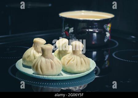 Hausgemachte, traditionelle asiatische Knödel und Topf auf schwarzem Hintergrund Stockfoto