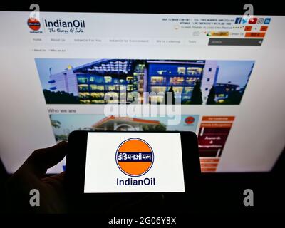 Person, die Mobiltelefon mit dem Logo des Mineralölunternehmens Indian Oil Corporation Ltd auf dem Bildschirm vor der Business-Webseite hält. Konzentrieren Sie sich auf die Telefonanzeige. Stockfoto