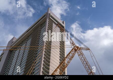 Hohes Gebäude mit Kran vorne und blauem Himmel Hintergrund Stockfoto