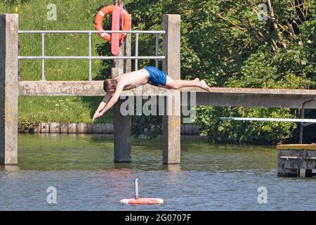 Ein Mann taucht am 1. Juni 2021 in den Hampstead Mens Pond Hampstead Heath, North London, ein, während sich das Wetter in ganz Großbritannien weiter aufheizt. Stockfoto