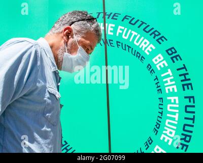 Am 1. Juni 2021 laufen Menschen in kovidierten Masken auf der Oxford Street an einem Schild mit der Aufschrift „BE THE FUTURE“ vorbei. Stockfoto