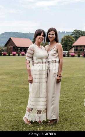 Porträt von zwei schönen Frauen in stilvollen Kleidern auf dem Rasen stehen. Stockfoto