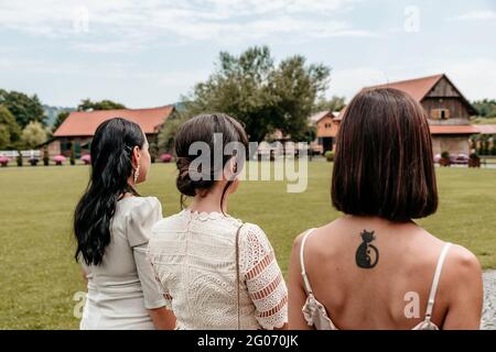 Rückansicht von drei jungen Frauen mit schönen Frisuren tragen stilvolle Abendkleider. Stockfoto