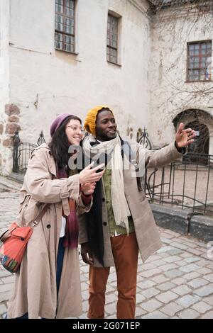 Fröhliche junge Touristen, die in der Stadt Sightseeing machen und Fotos am Telefon machen Stockfoto
