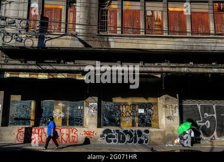 Eine Frau geht an einem alten, verfallenden, mit Graffiti bedeckten Gebäude in der Chinatown-Gegend von Bangkok, Thailand, vorbei Stockfoto