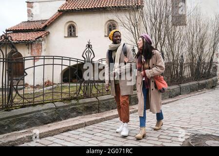 Junges multiethnisches Paar, das im Freien auf der Straße herumläuft und redet Stockfoto