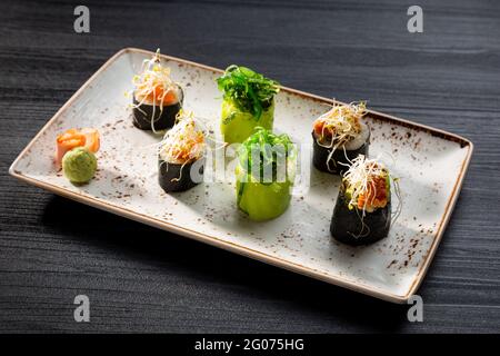 Nahaufnahme von verschiedenen Sushi-Rollen auf dunklem Hintergrund, typisch japanisches Essen. Stockfoto