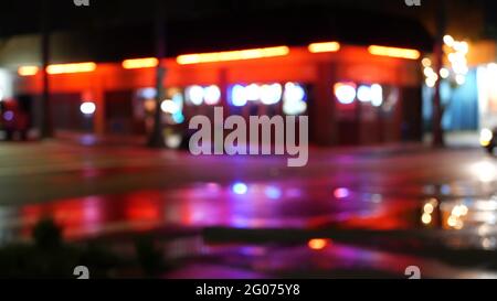 Unscharfe Abendstraße, verschwommenes Bokeh. Lichter der Stadt und Autos in regnerischer Nacht. Spiegelung von elektrischen Lampen. Automobile auf der Straße im weichen Fokus. Wirbel Stockfoto