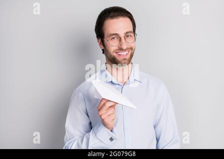 Portrait von attraktiven trendigen fröhlichen Mann Experte Agent Broker hält in Hand Papier Flugzeug isoliert über grauen Pastellfarben Hintergrund Stockfoto