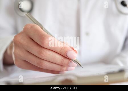 Der Arzt schreibt die Krankengeschichte des Patienten mit einem Stift auf die Karte Stockfoto