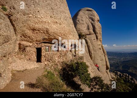 Eremitage von Sant Salvador in einer Höhle in der Felswand des Elefant, wo ein Bergsteiger hinaufgeht (Montserrat, Barcelona, Katalonien, Spanien) Stockfoto