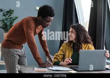 Zwei Kollegen aus dem Unternehmen diskutieren gemeinsam und nutzen ihren Laptop bei der Arbeit Stockfoto