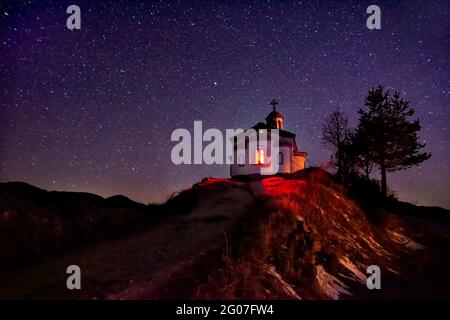 Kleine Kapelle auf dem Hügel in Rhodope Berg in der Nähe Borovo Dorf. Bulgarien.Nacht Sternenhimmel, blau leuchtenden Raum. Abstrakter Hintergrund mit Sternen, Kosmos Stockfoto
