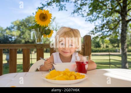 Kind, Kleinkind Junge, mit Frühstück am Morgen, sitzen auf der Veranda von Camping van, Reisen Sommerzeit, Familienurlaub Stockfoto