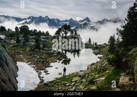 Gipfel des Aigüestortes-Nationalparks, in den Pyrenäen, im Sommer nebliger Sonnenaufgang, von einem See in der Nähe der Amitges-Hütte aus gesehen (Pallars Sobirà, Cataluña) Stockfoto