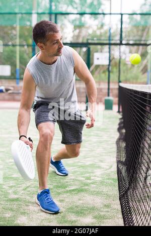 Junger erwachsener Mann, der im Freien Paddeltennis spielt Stockfoto
