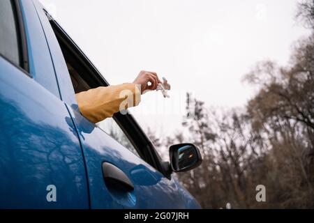 Beschnittene Ansicht eines Mannes, der gebrauchte Serviette aus dem Auto wegwirft Stockfoto