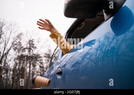 Beschnittene Ansicht eines Mannes, der leere Papiertasse aus dem Auto wegwirft Stockfoto